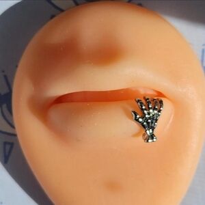 Brand new Silver Toned skeleton hand lip ring. Threaded.